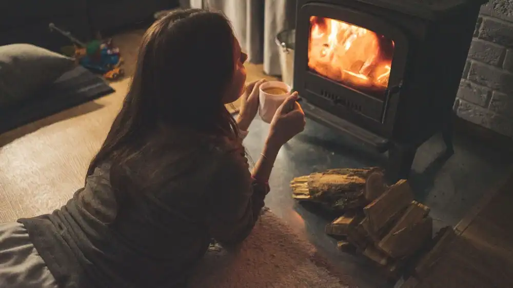 Person warming up beside a home wood-burning stove